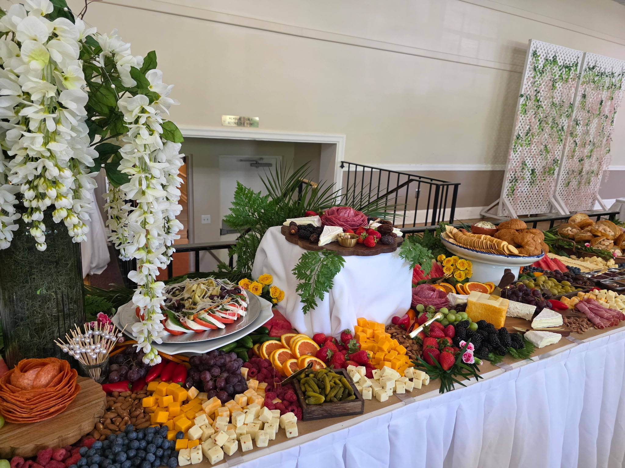 A lodge-catered spread of cheeses, fruit, sliced meats, crackers, sandwiches, and floral decorations.