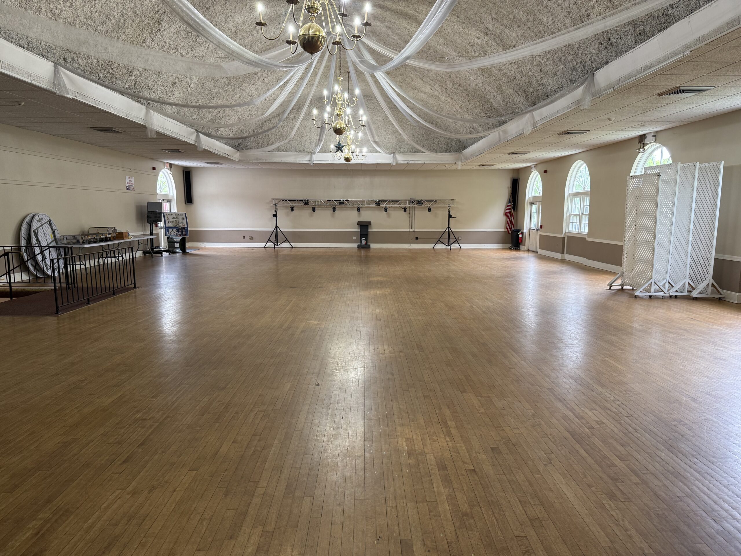 The open banquet hall showing the wood floor, arched windows, and chandeliers.